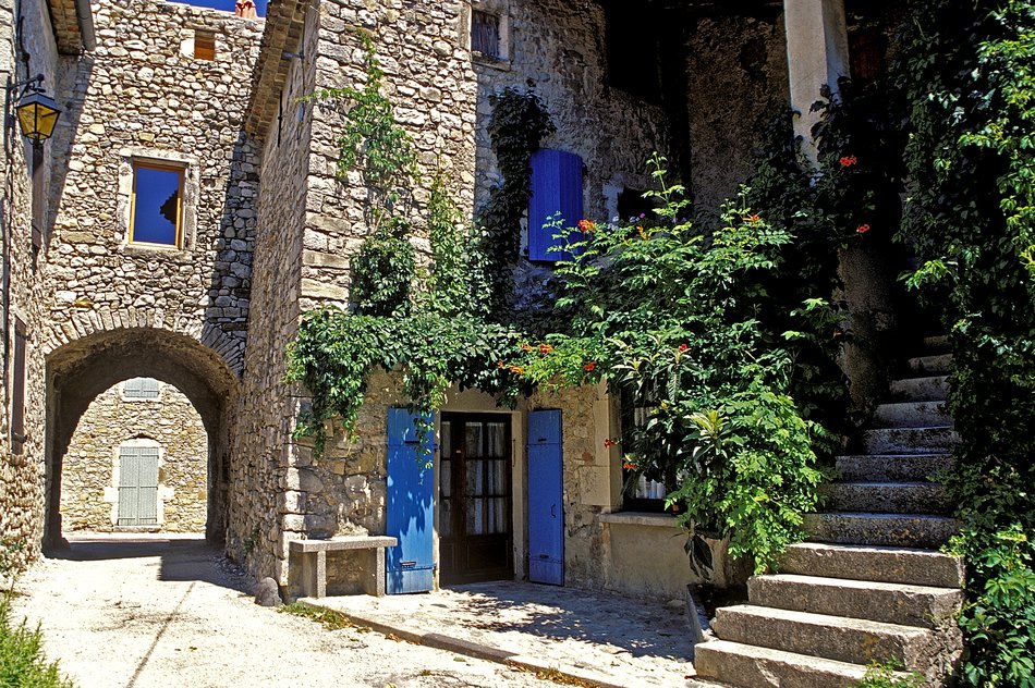 The village centre and historic alleyways of Valvignères, featuring an archway and stone houses