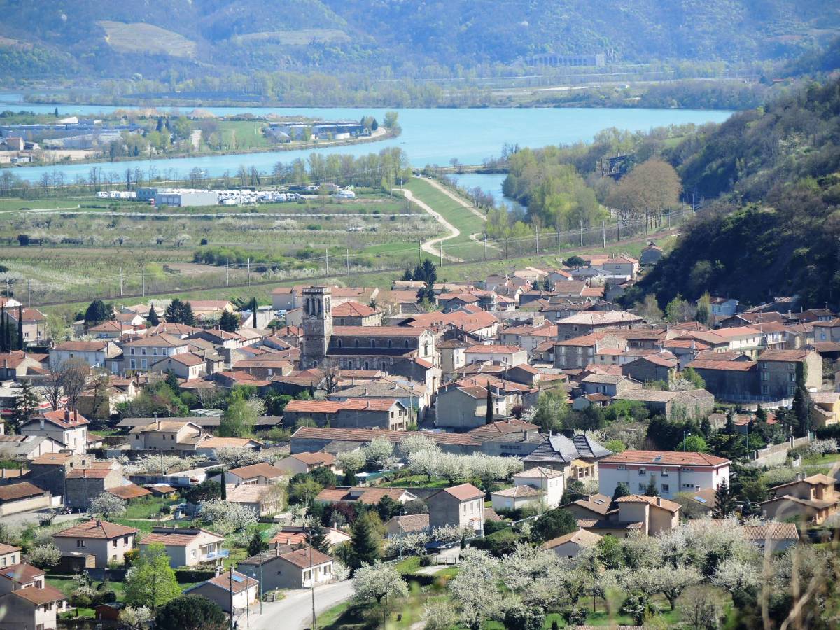 Photo of the village of Sarras in the Ardèche with the Rhône River in the background, the railway and the fields in between.